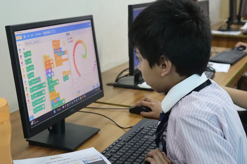 A learner building a Scratch project on a classroom computer