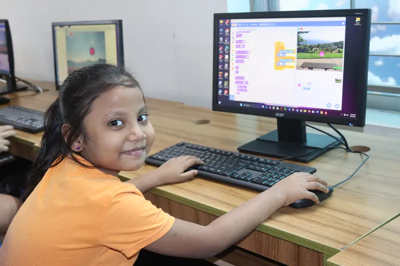 A learner proudly showing her Scratch project at MyeKids