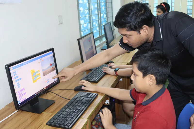 A mentor helping a young learner explore Scratch in class