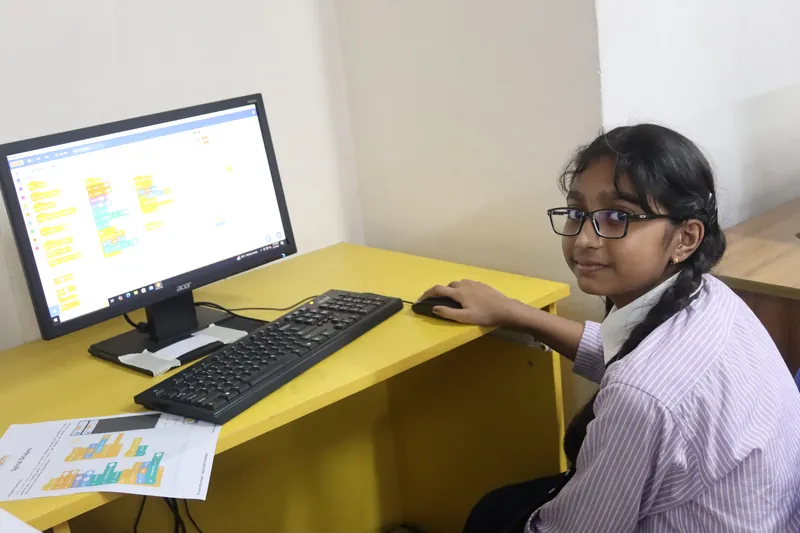 A MyeKids learner sharing her project at a classroom computer